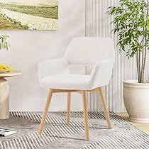 a white chair sitting in front of a painting on the wall next to a table