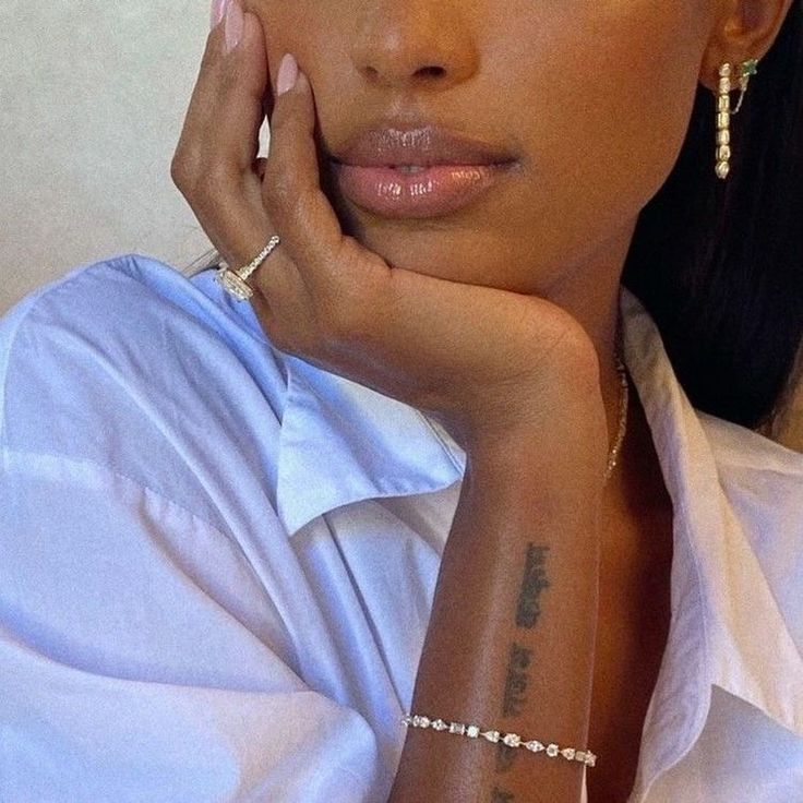 a close up of a person with a tattoo on her arm and wearing a white shirt