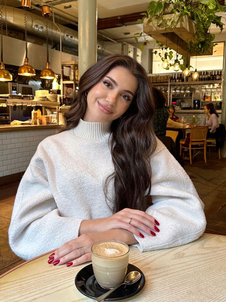 a woman sitting at a table with a cup of coffee