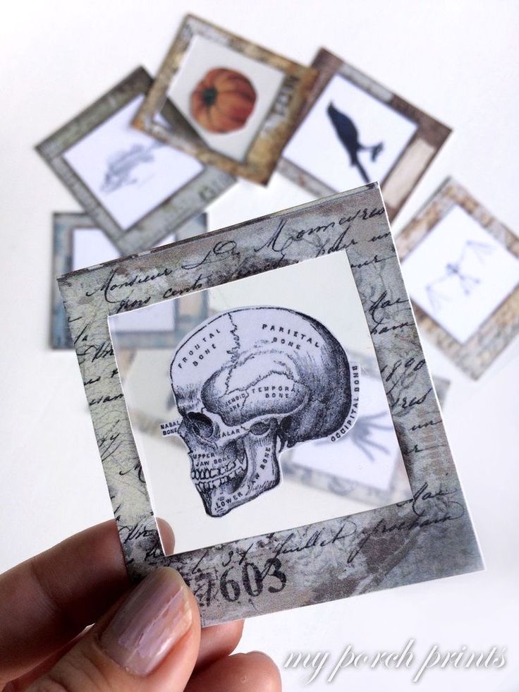 a hand holding up a small card with an image of a skull on it