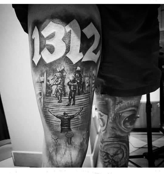 black and white photo of a man's leg with his arm covered in tattoos