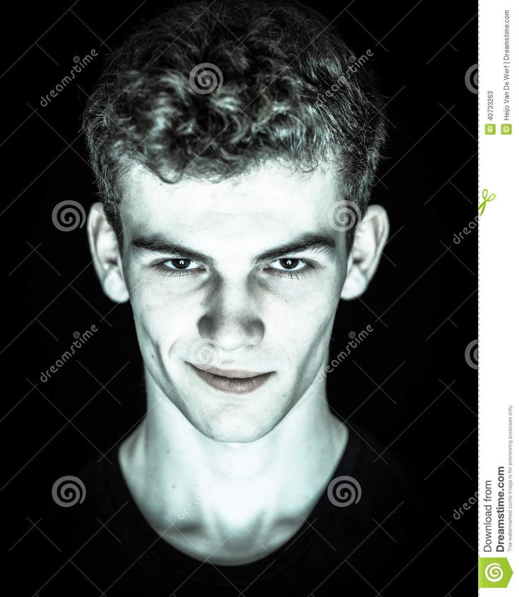 a black and white photo of a young man with curly hair smiling at the camera