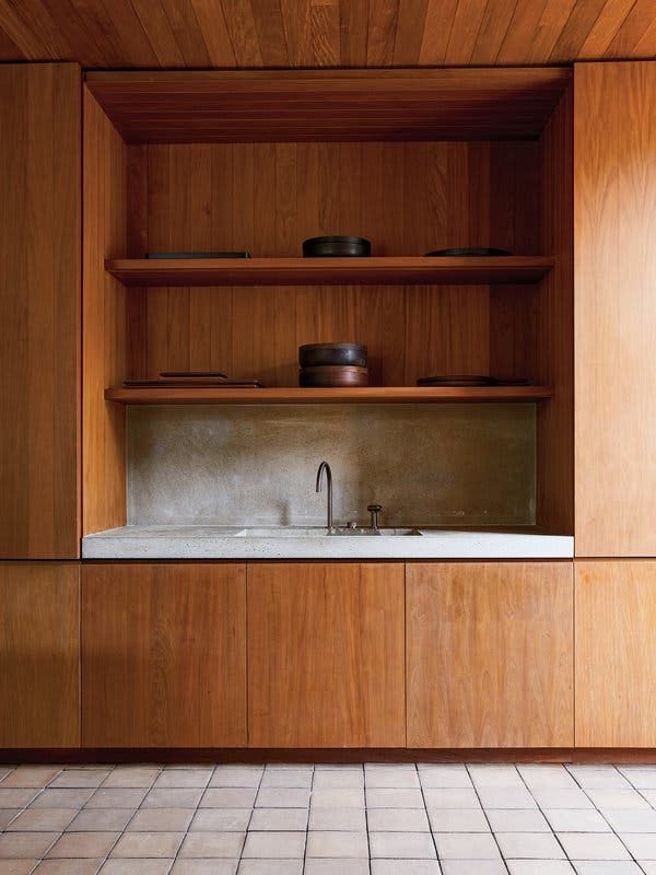 an empty kitchen with wooden cabinets and white tile flooring on the walls, along with a stainless steel faucet