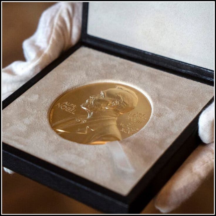 a close up of a person holding a gold coin in a box on a table