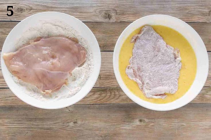 two white bowls filled with food on top of a wooden table