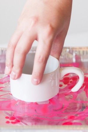 a person's hand reaching into a coffee cup on a pink and white tray