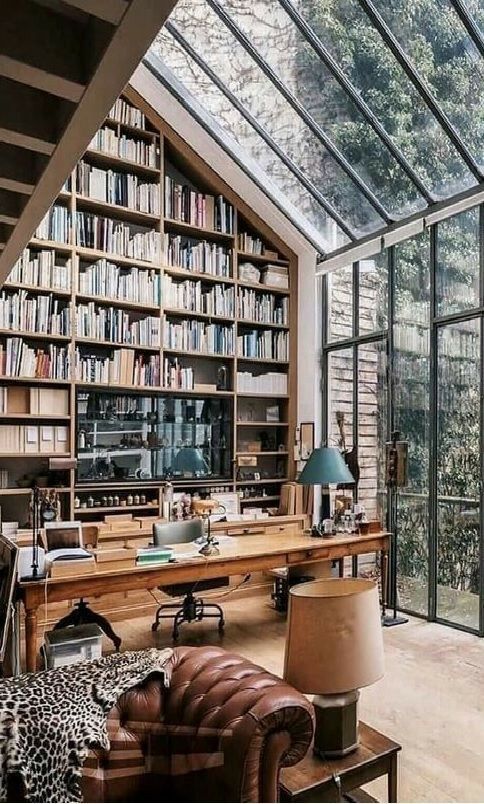 a living room filled with lots of furniture and bookshelves next to a window