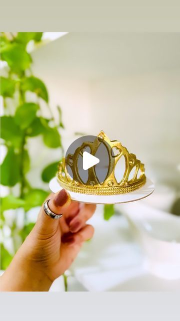 a hand holding a white plate with a gold crown on it and a video player in the middle