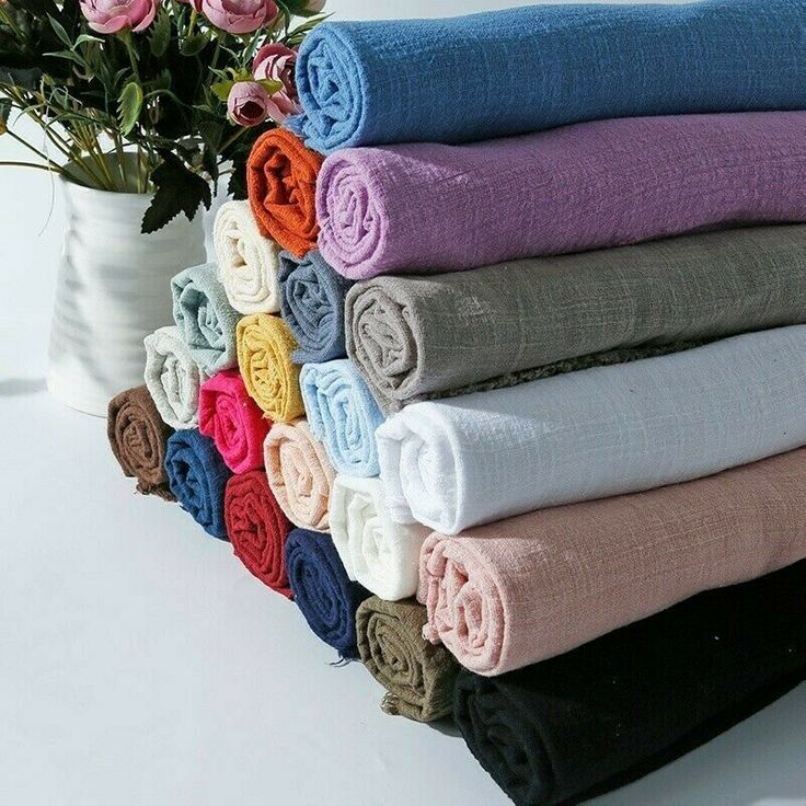 a stack of folded towels sitting on top of a white table next to a potted plant