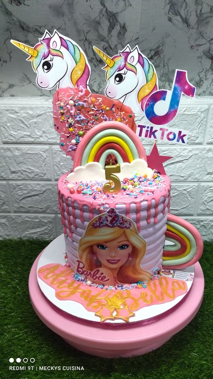 a birthday cake decorated with pink icing and sprinkles is on display