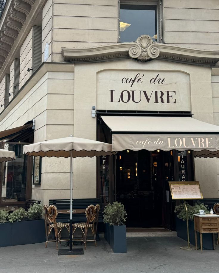 an outside view of a cafe with tables and umbrellas on the sidewalk in front of it