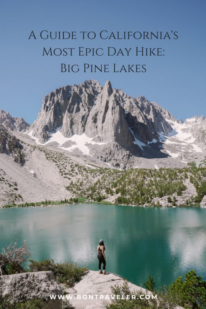 a person standing on top of a mountain next to a lake with mountains in the background