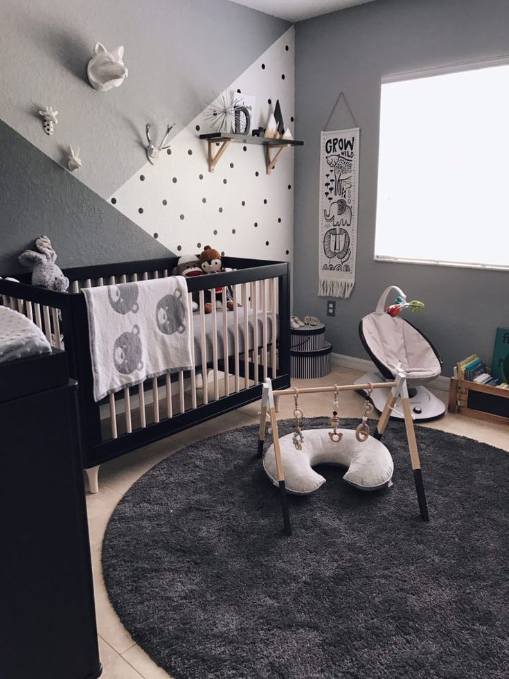 a baby's room with grey walls and black carpet, white crib bedding