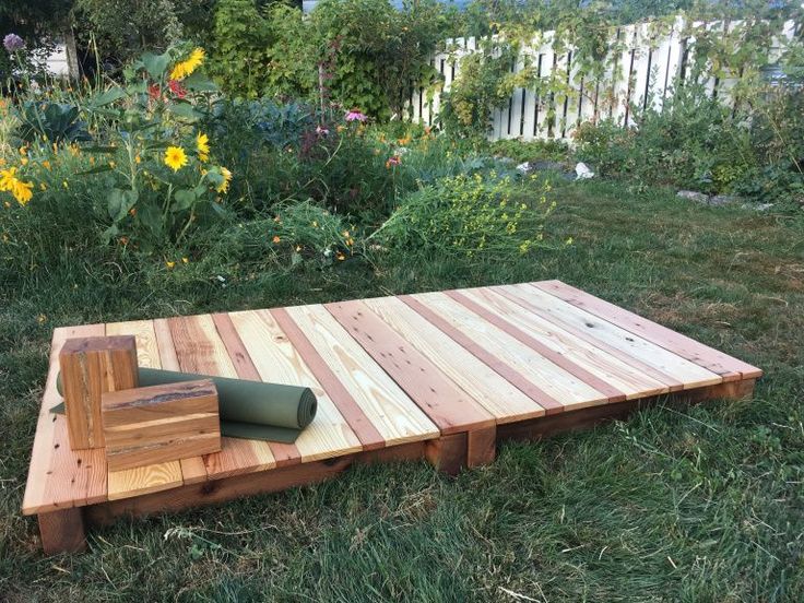 a wooden pallet sitting on top of a lush green field next to a flower garden