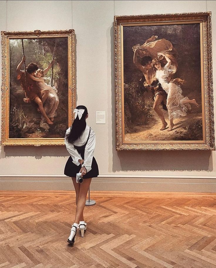 a woman standing in front of two paintings