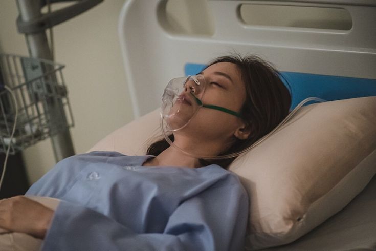 a woman laying in a hospital bed with an oxygen tube attached to her head and breathing mask on