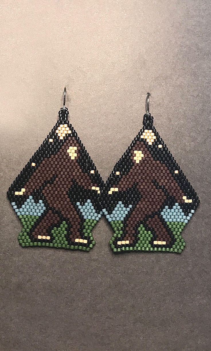 a pair of brown and blue beaded earrings on top of a gray surface,