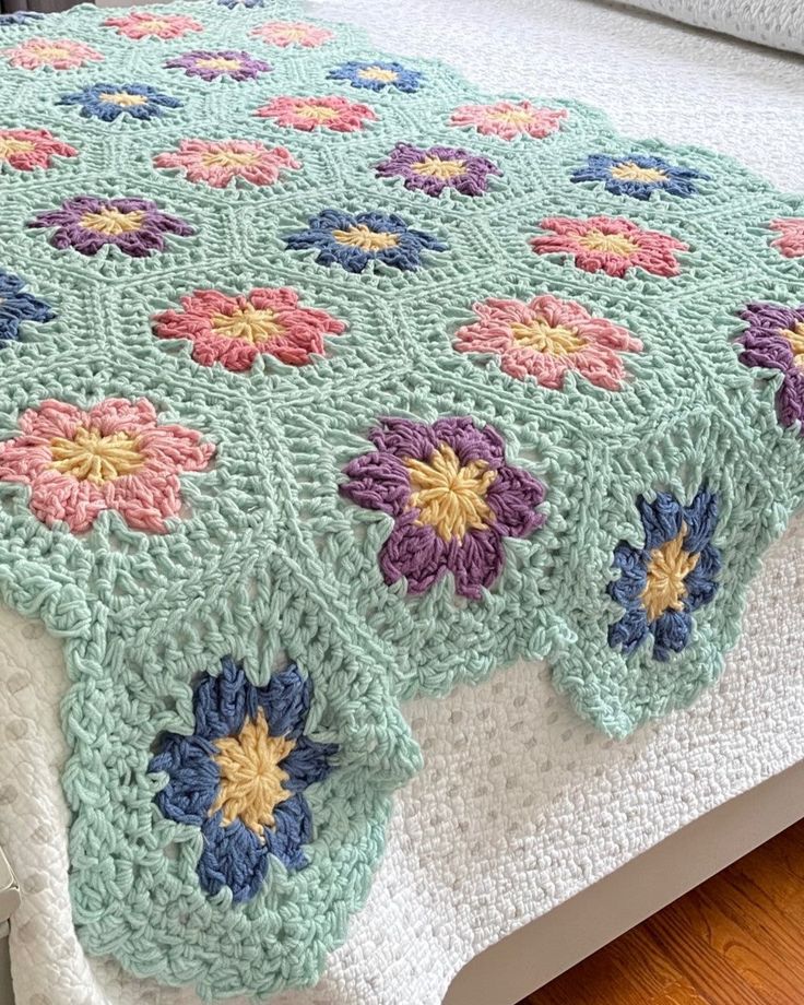 a crocheted bedspread with colorful flowers on the top and bottom, sitting on a bed