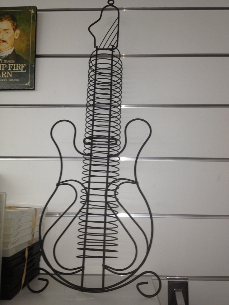 a metal guitar sculpture sitting on top of a white table next to a book shelf