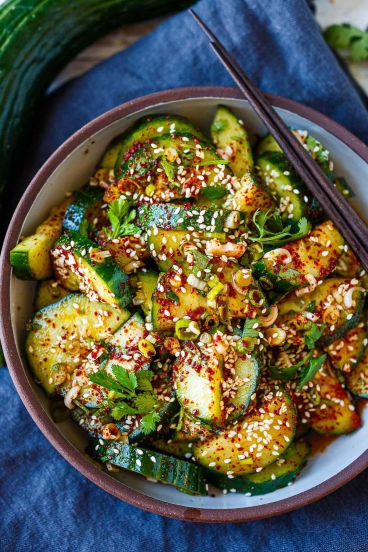 a bowl filled with vegetables and chopsticks on top of a blue table cloth