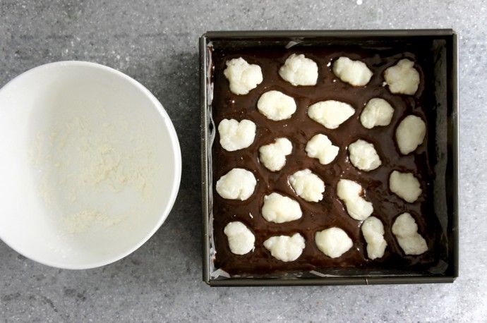 a pan filled with chocolate and marshmallows next to a bowl of sugar