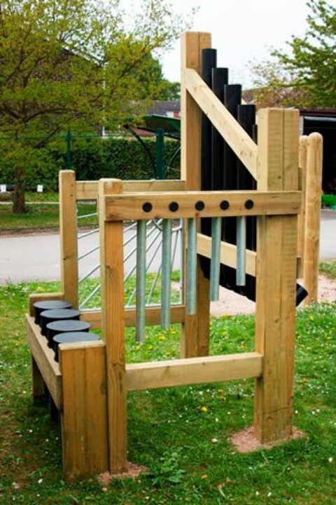 a wooden play structure with black and white railings on the grass next to trees