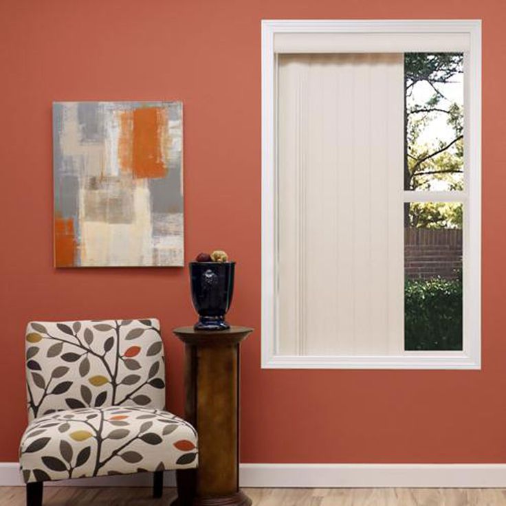 a living room with an orange wall and white blinds