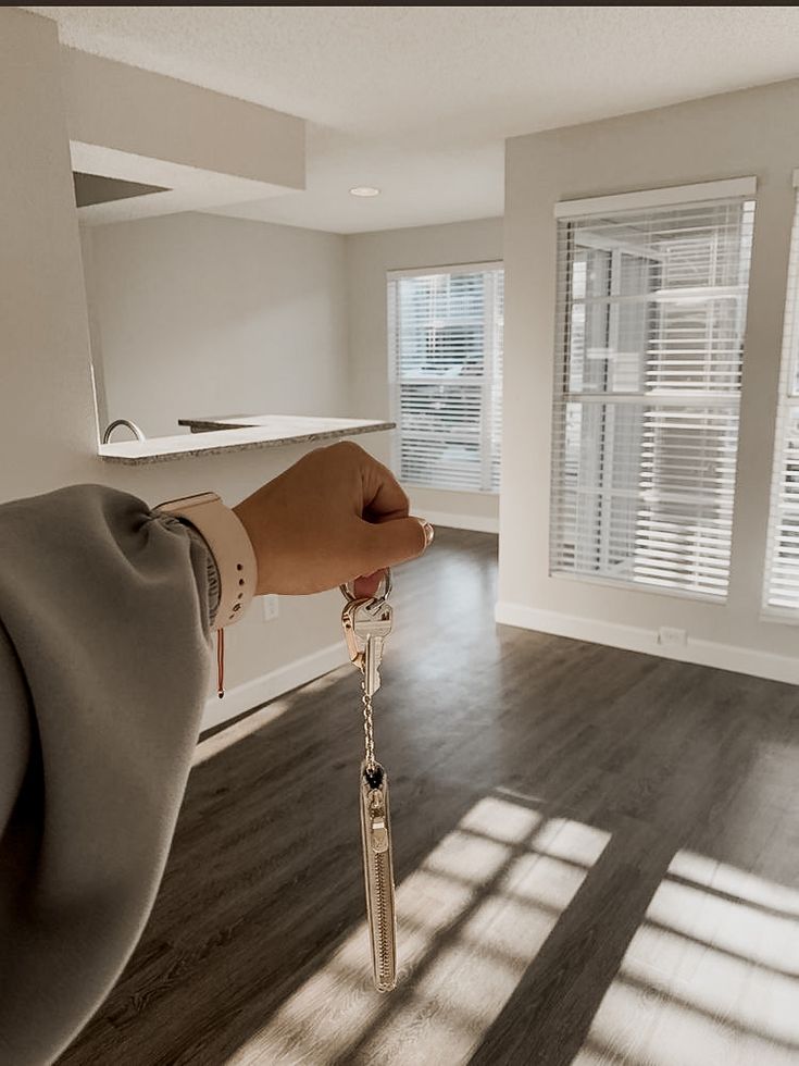 a person's hand holding a key in an empty room