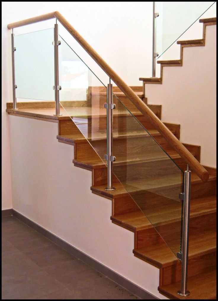 a set of stairs with glass railings and wood handrail