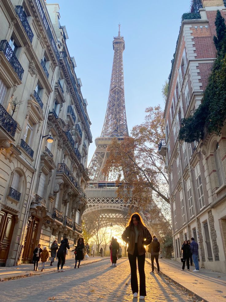 the eiffel tower is in the background as people walk down an alley way