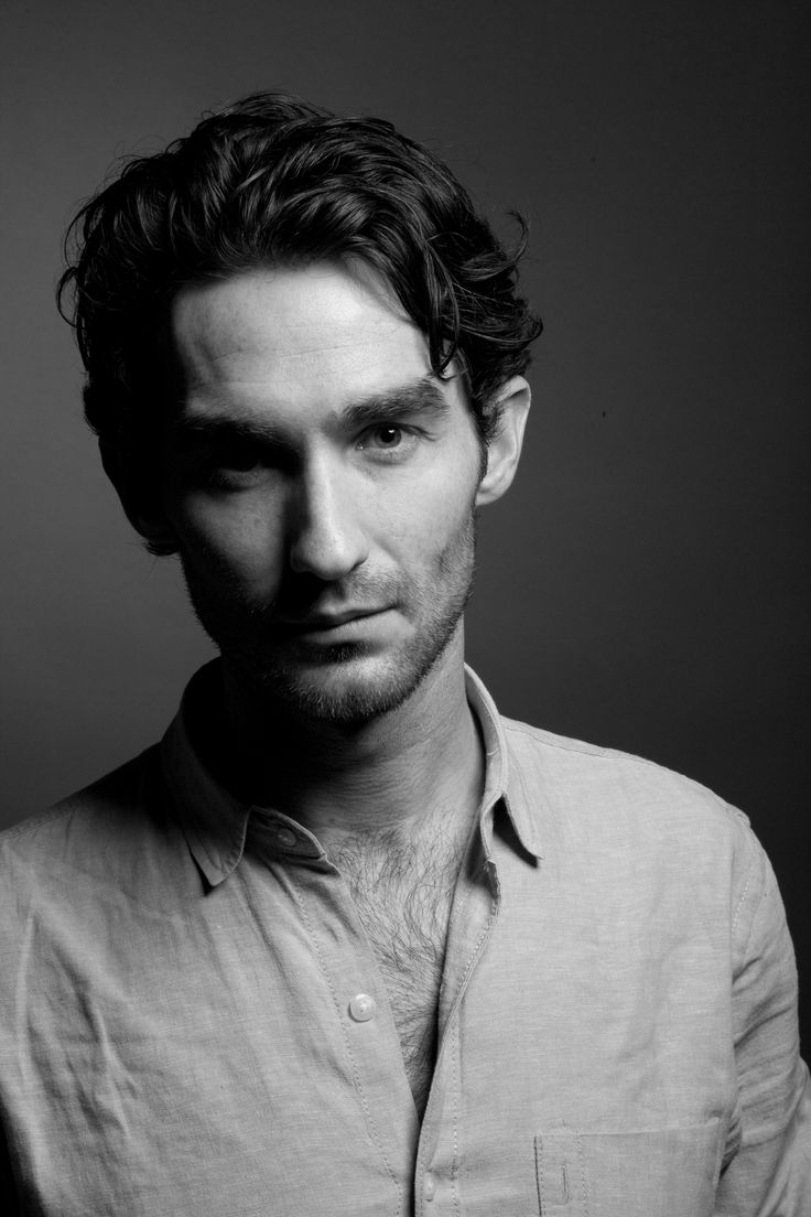 a black and white photo of a man in a button up shirt looking at the camera