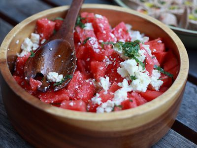 a wooden bowl filled with watermelon and feta cheese