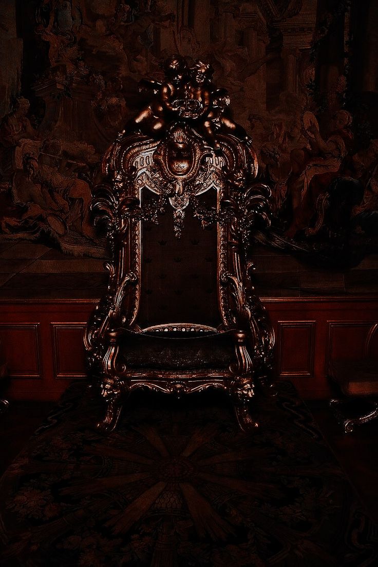 an ornate gold chair sitting in front of a painting