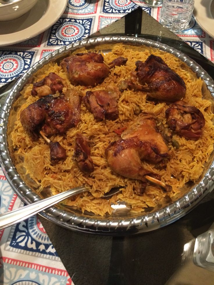 a large metal pan filled with food on top of a table next to silverware