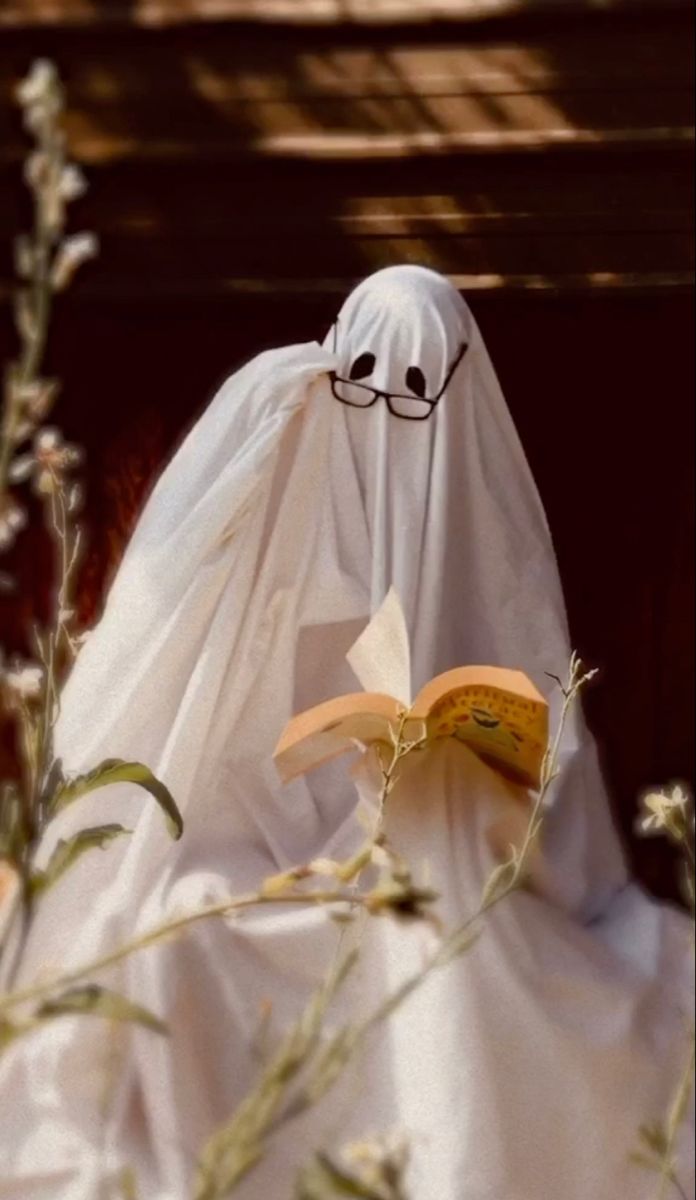 a ghost reading a book while wearing glasses and a white cloth covering it's face