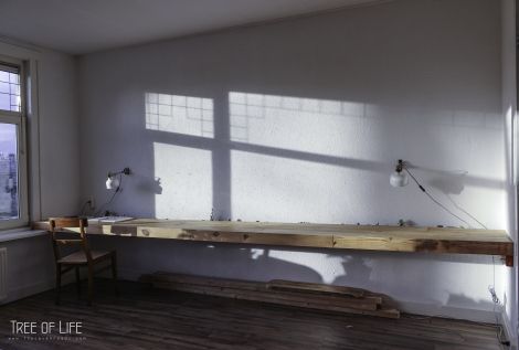 an empty room with two windows and a wooden bench in the corner, next to a window