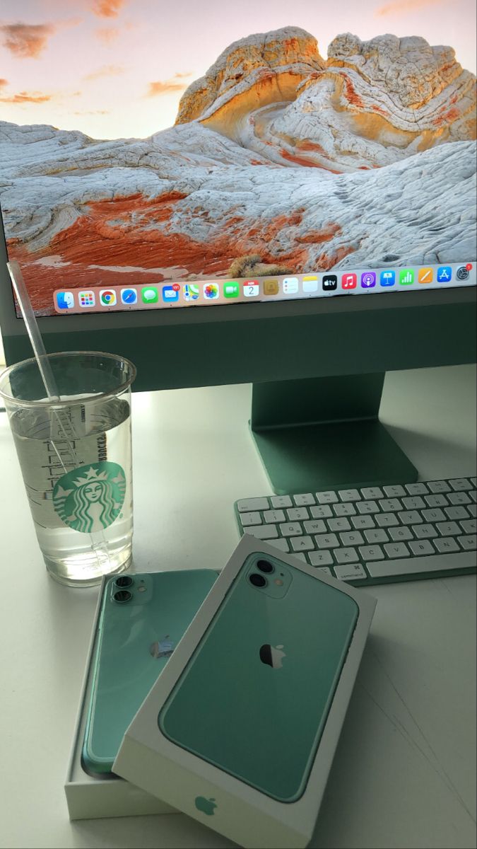 an apple computer monitor sitting on top of a desk next to a cup and keyboard