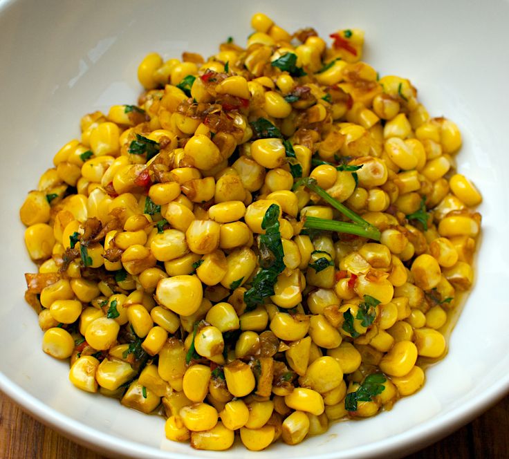 a white bowl filled with corn on top of a wooden table