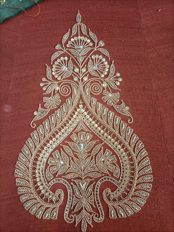 a piece of cloth with an intricate design on the front and side of it in gold thread