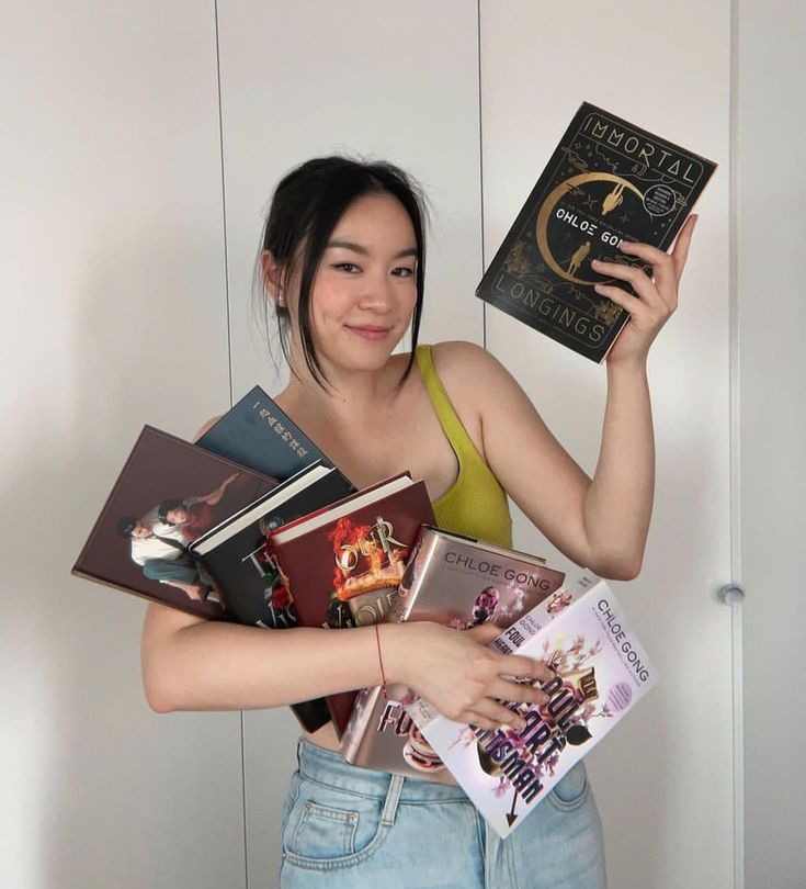 a woman is holding several books in her hands