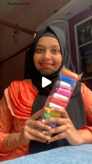 a woman in a hijab holding a box of crayons