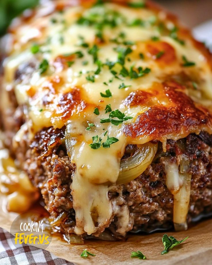 a cheesy meatloaf casserole with cheese and onions on a cutting board