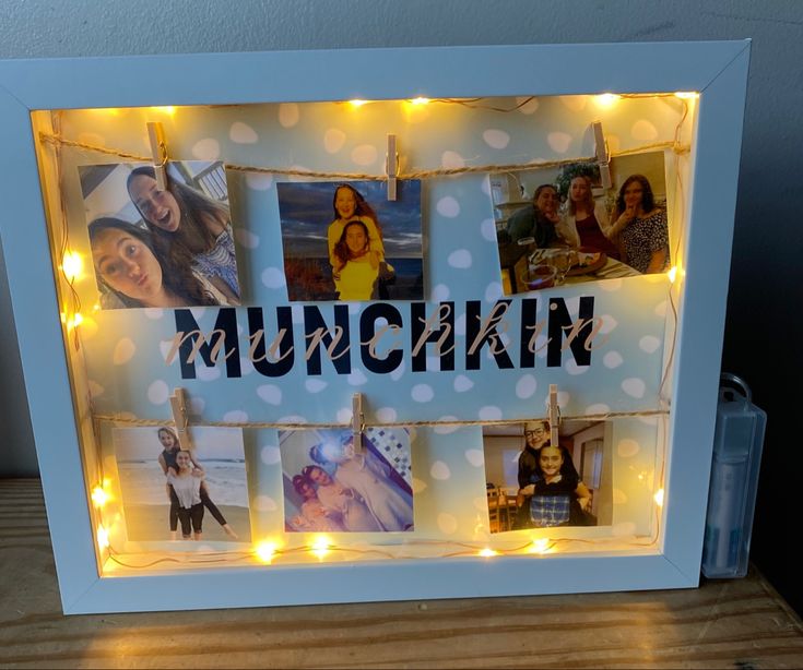 an illuminated photo frame with the word munchkin surrounded by photos and lights on a wooden table