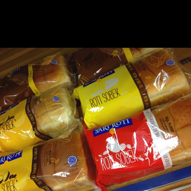 several bags of bread sitting on top of a wooden table