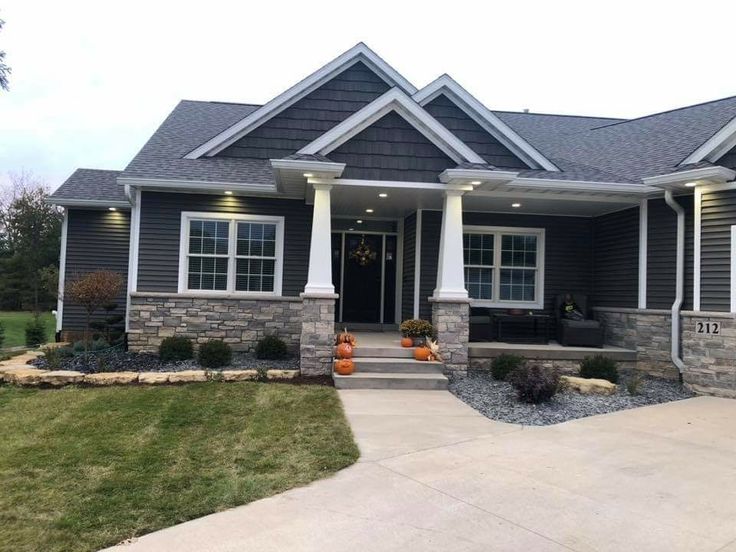 a gray house with white columns and two front porches on the side of it