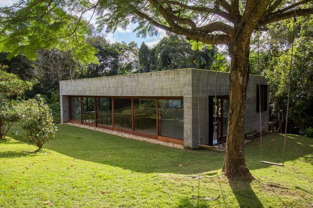 a concrete house in the middle of a lush green field with trees and grass around it