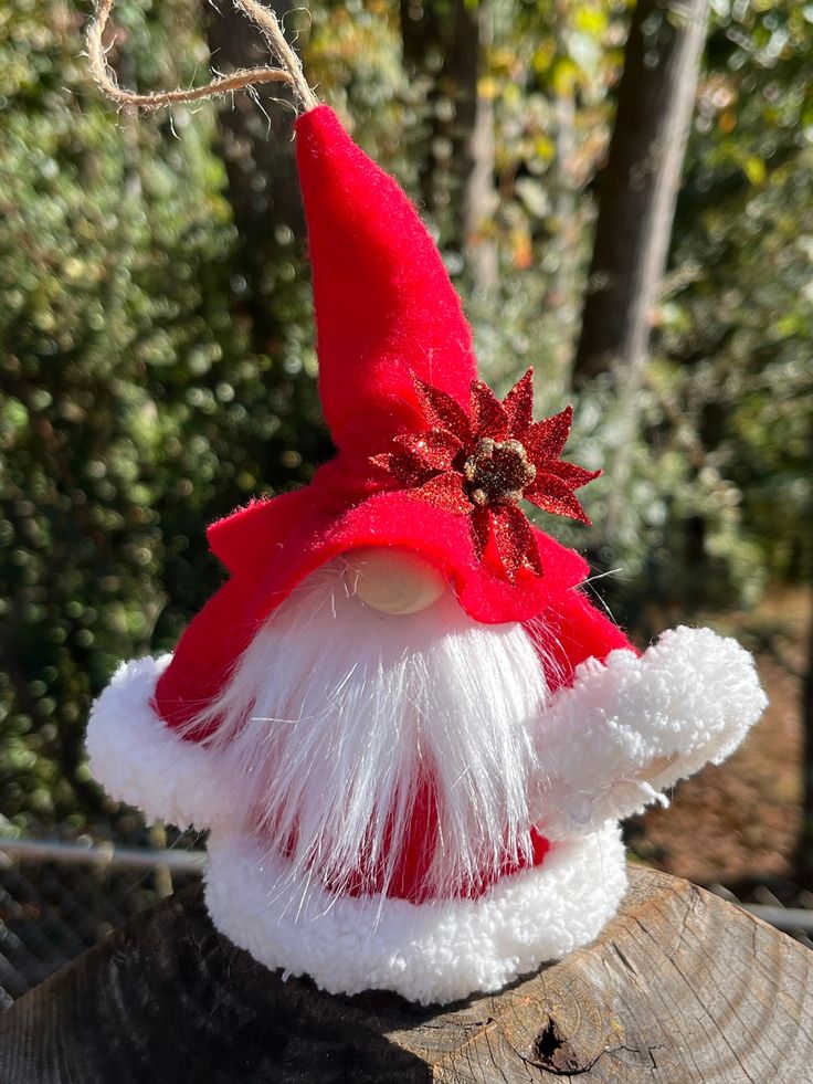 a red and white santa hat sitting on top of a tree stump