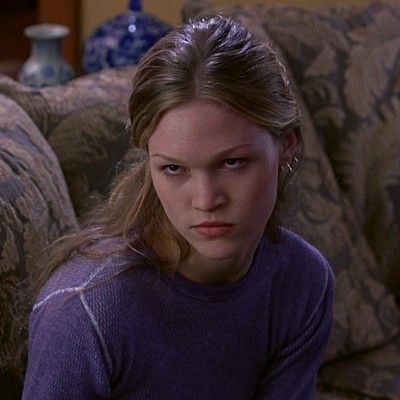 a young woman sitting on top of a couch in front of a tv remote control