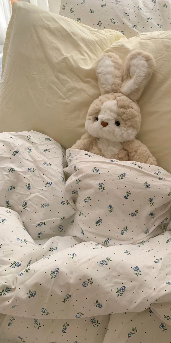 a stuffed animal sitting on top of a bed covered in white sheets and pillow cases