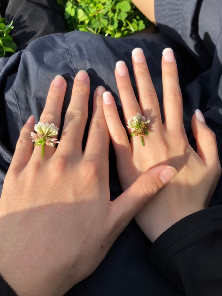 two hands holding each other with flowers on their fingers and one hand in the air